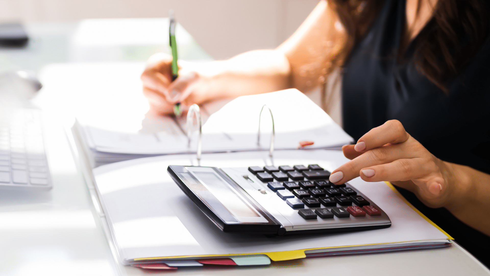 An image of a female business owner with a calculator working on her accounts receivables